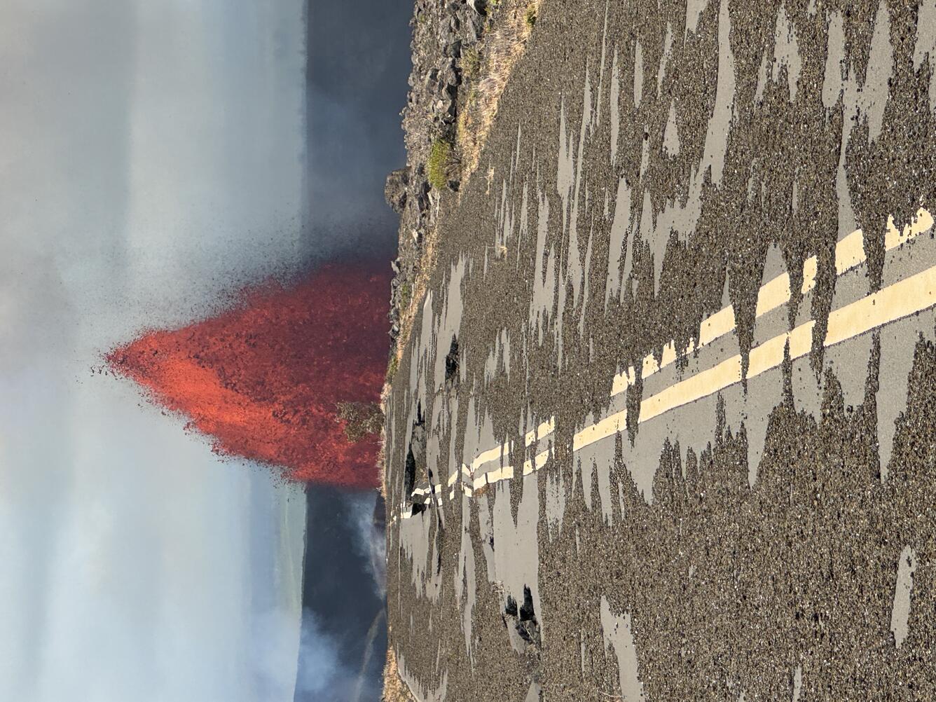 Color photograph of lava fountain with broken road in foreground