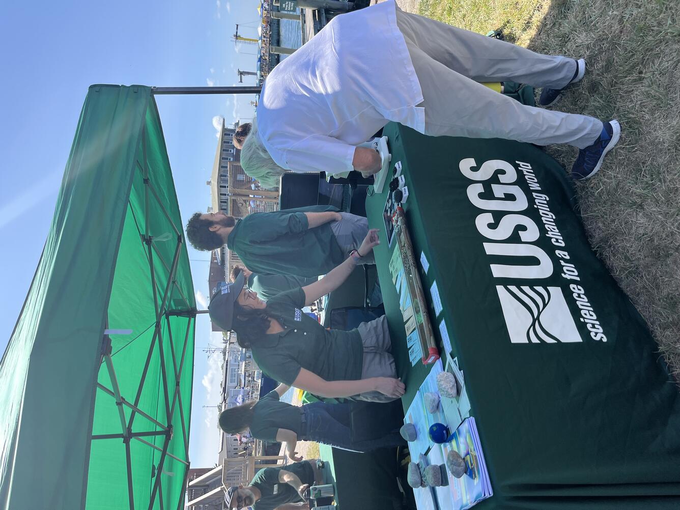 person at USGS booth talking to attendee who is looking at items on the table