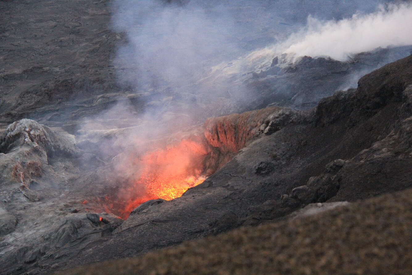 Color photo of lava spattering out of the north vent. The lava appears orange due to it's high temperature. 
