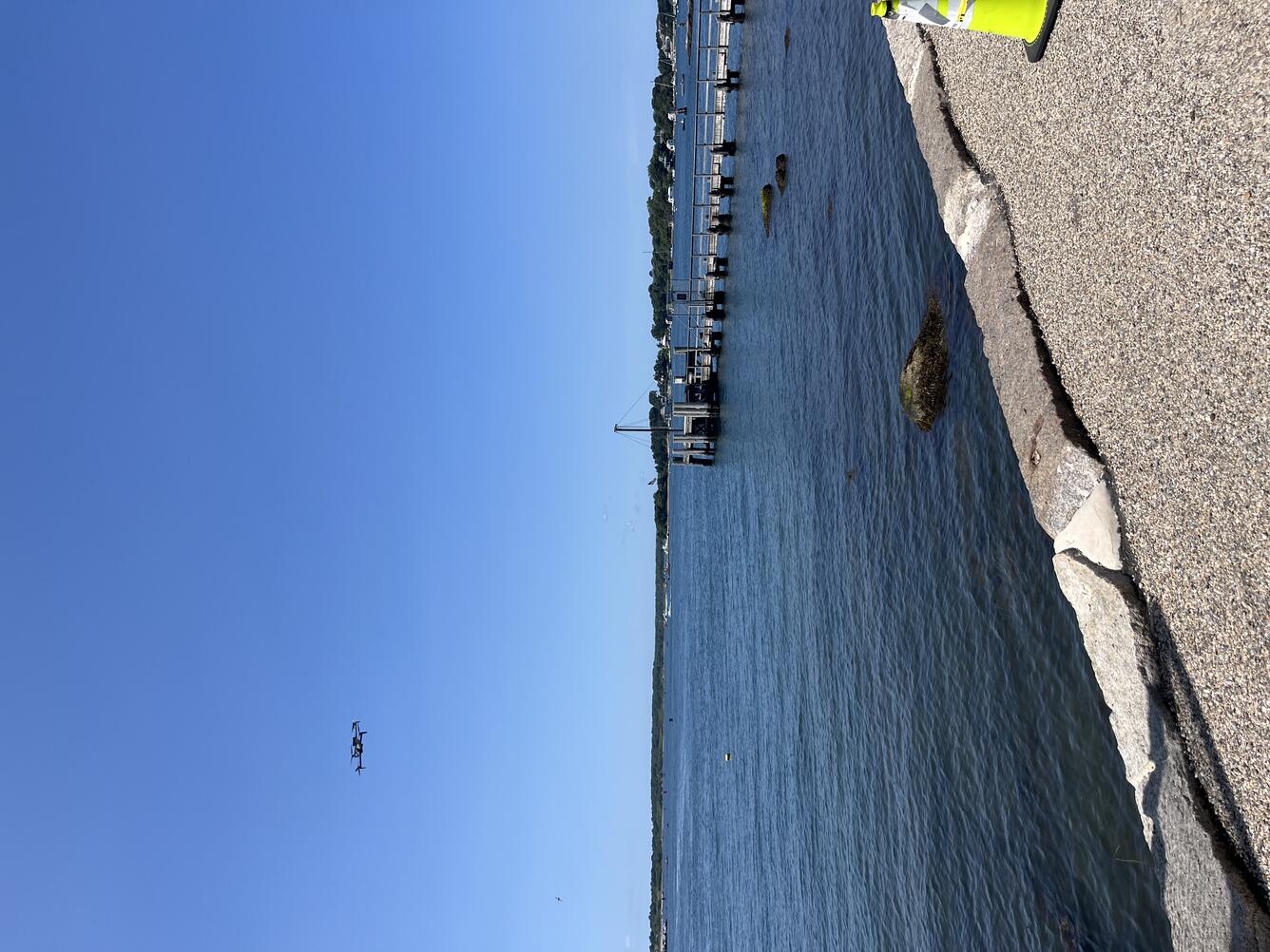 drone flying in the air over the ocean near the shore