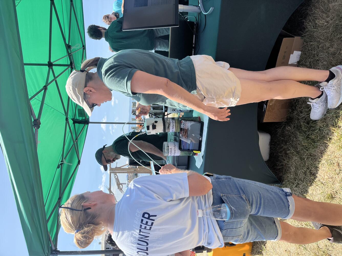 USGS scientist talking to person outside at a USGS booth under a tent