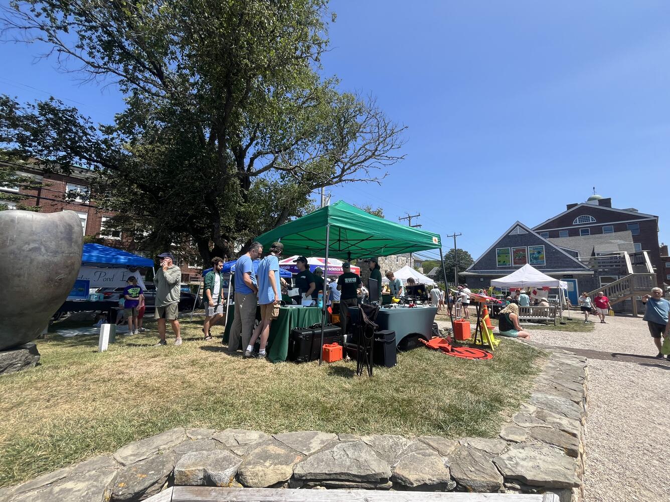 USGS tent and four tables with people visiting the booths to talk to the scientists