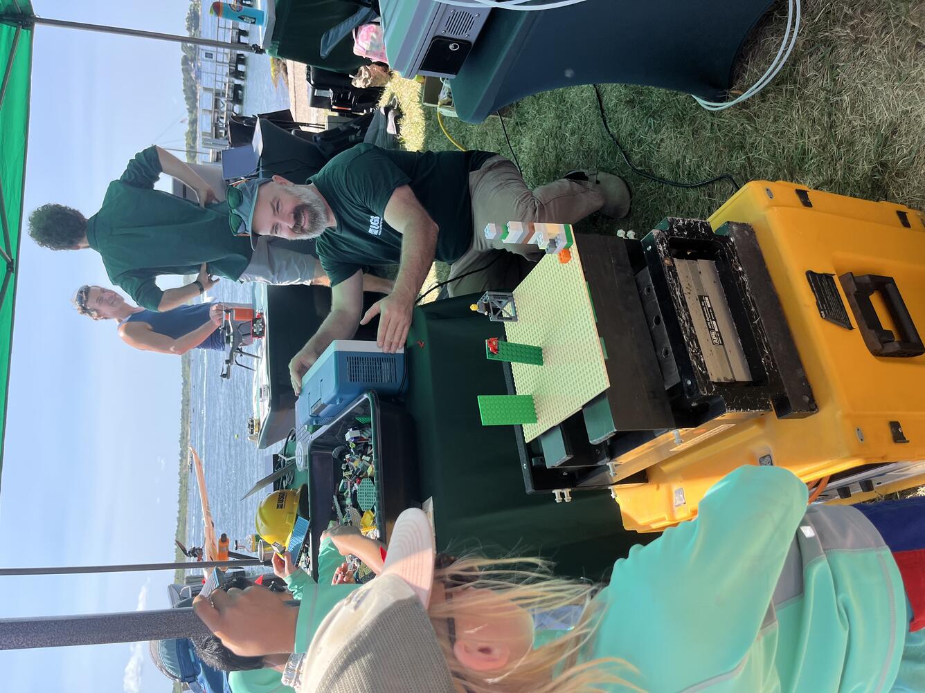 people in USGS shirt smiling at child using the earthquake shake table