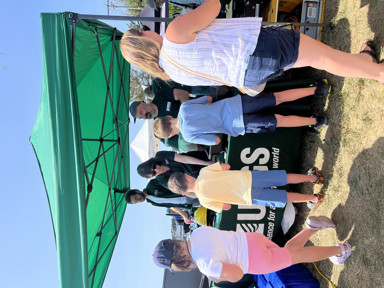 people visiting USGS booth outside under tent