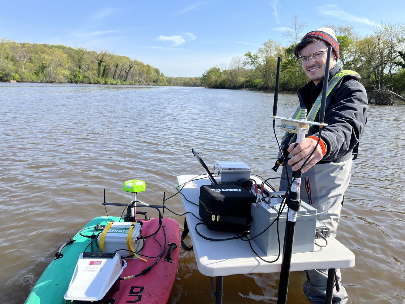 A hydrologic technician poses with an autonomous miniature boat in the Anacostia River.
