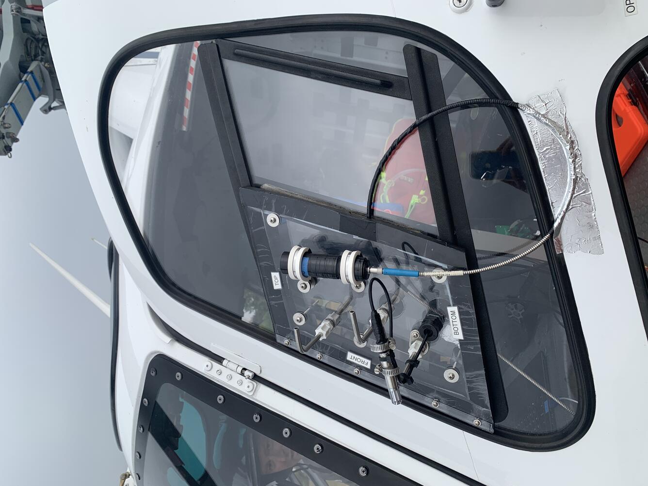 Color photo of the sampling equipment connected to the window of the helicopter. 