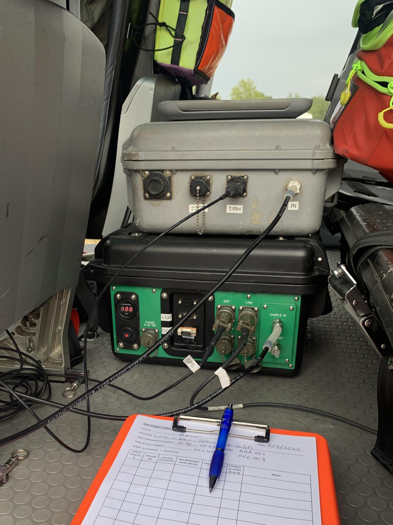 Color photo of gas monitoring tools inside the helicopter with a notebook. 
