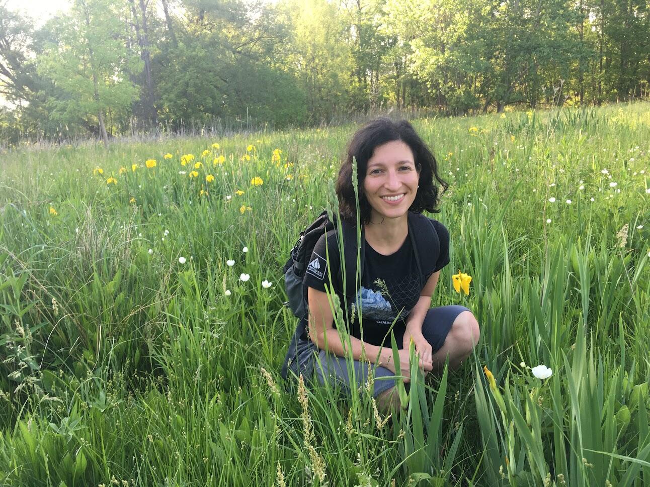 Eleni Petrou in a field of wild flowers with trees in the background