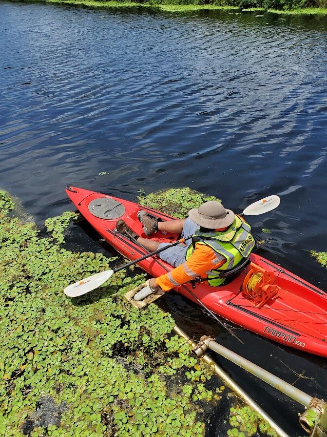 USGS employee cleans uplooking ADVM mount for Index Velocity gaging station. 