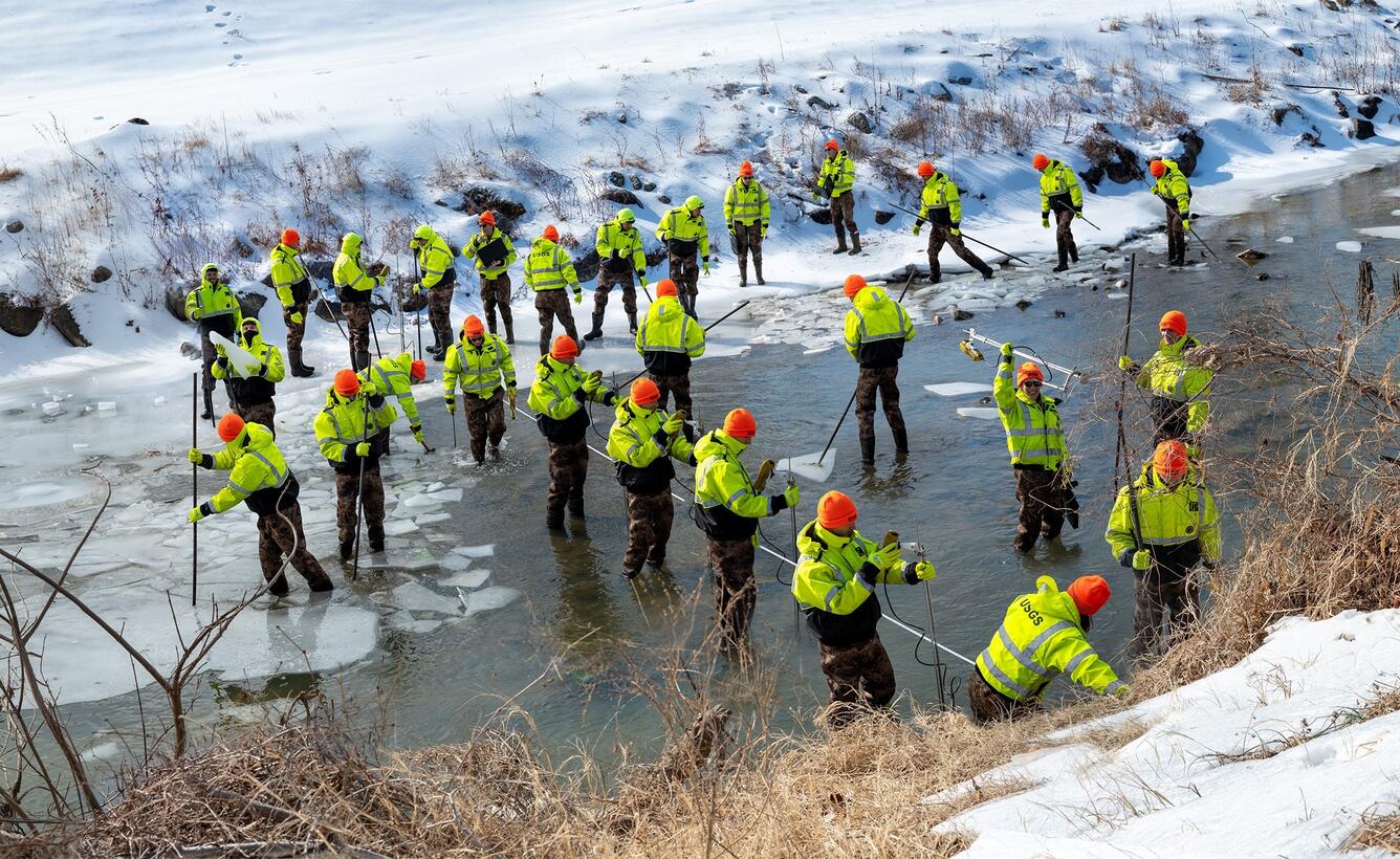A photo composite of 35 images showing hydrologic technicians breaking up an ice and measuring streamflow.