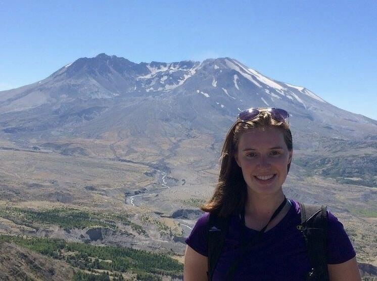 Woman standing in front of mountain with blue sky.