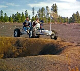 Photo of astronauts driving a lunar rover in the Cinder Lake Crater Field