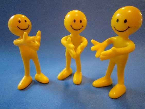 Three yellow smiling toys clapping
