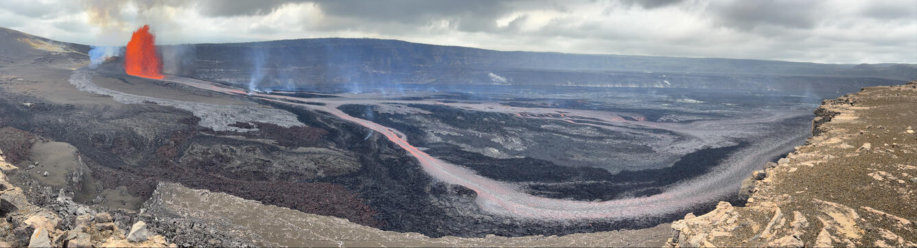 Color panoramic photograph of lava fountain and lava channel within volcanic crater