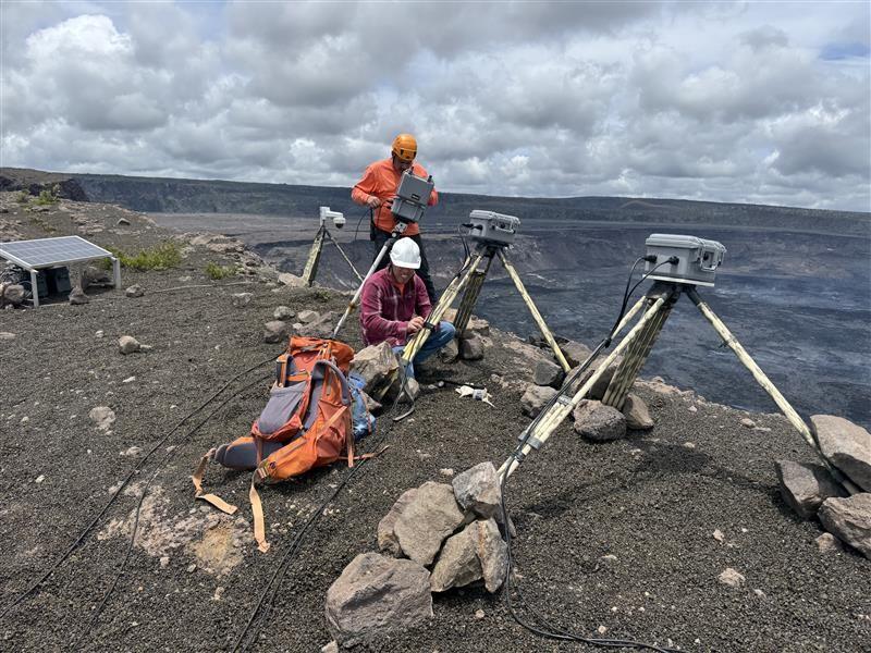 Color photograph of scientist installing webcameras on rim of volcano