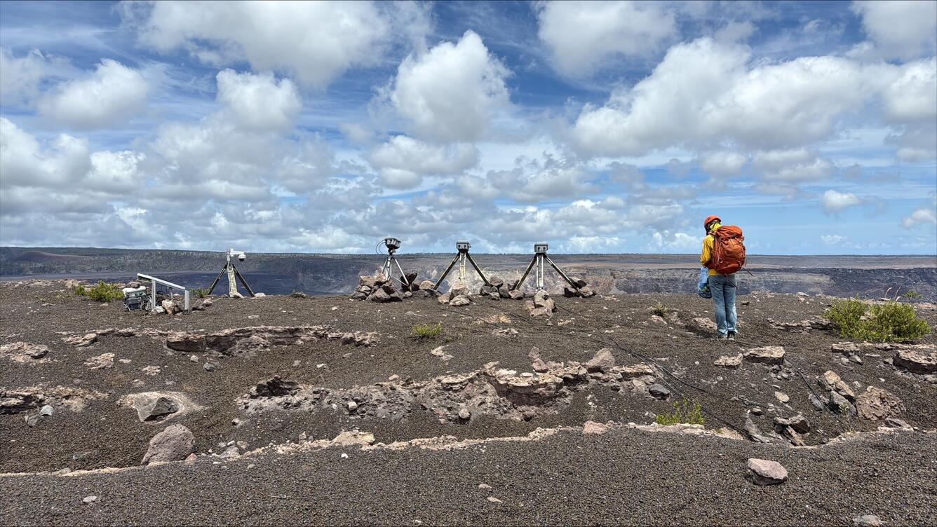 Color photograph of scientist near volcano monitoring equipment
