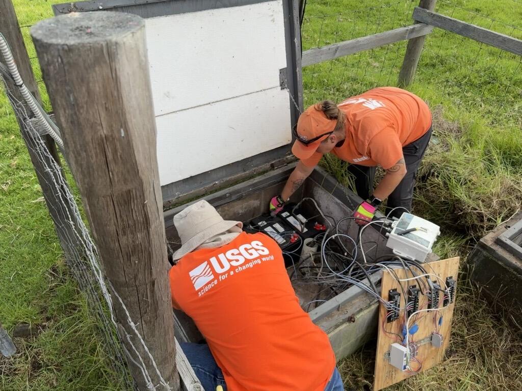 Color photograph of field engineers maintaining volcano monitoring instrumentation
