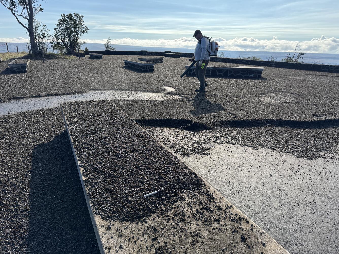 Color photograph of tephra fall out at a public overlook being cleaned with a leaf blower