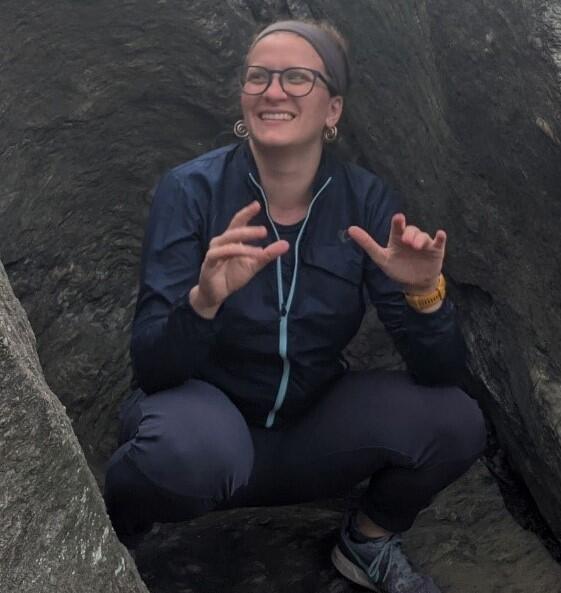 Photo of Libby crouching on some rocks.
