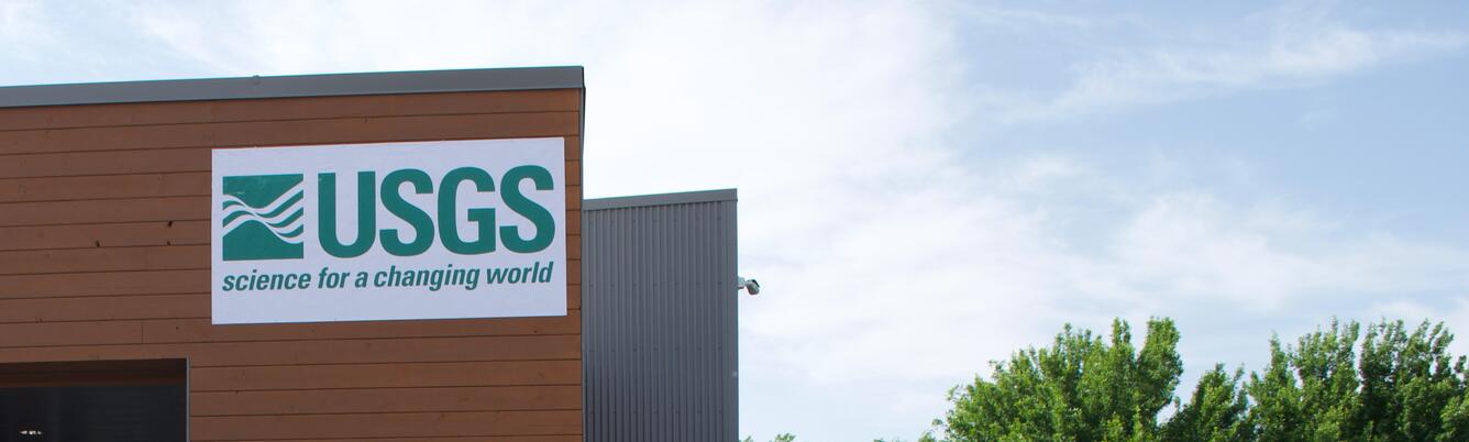 corner of a building with the USGS logo and trees in the background