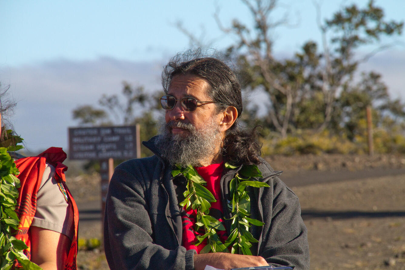 Man with brown hair and grey beard wearing a lei.