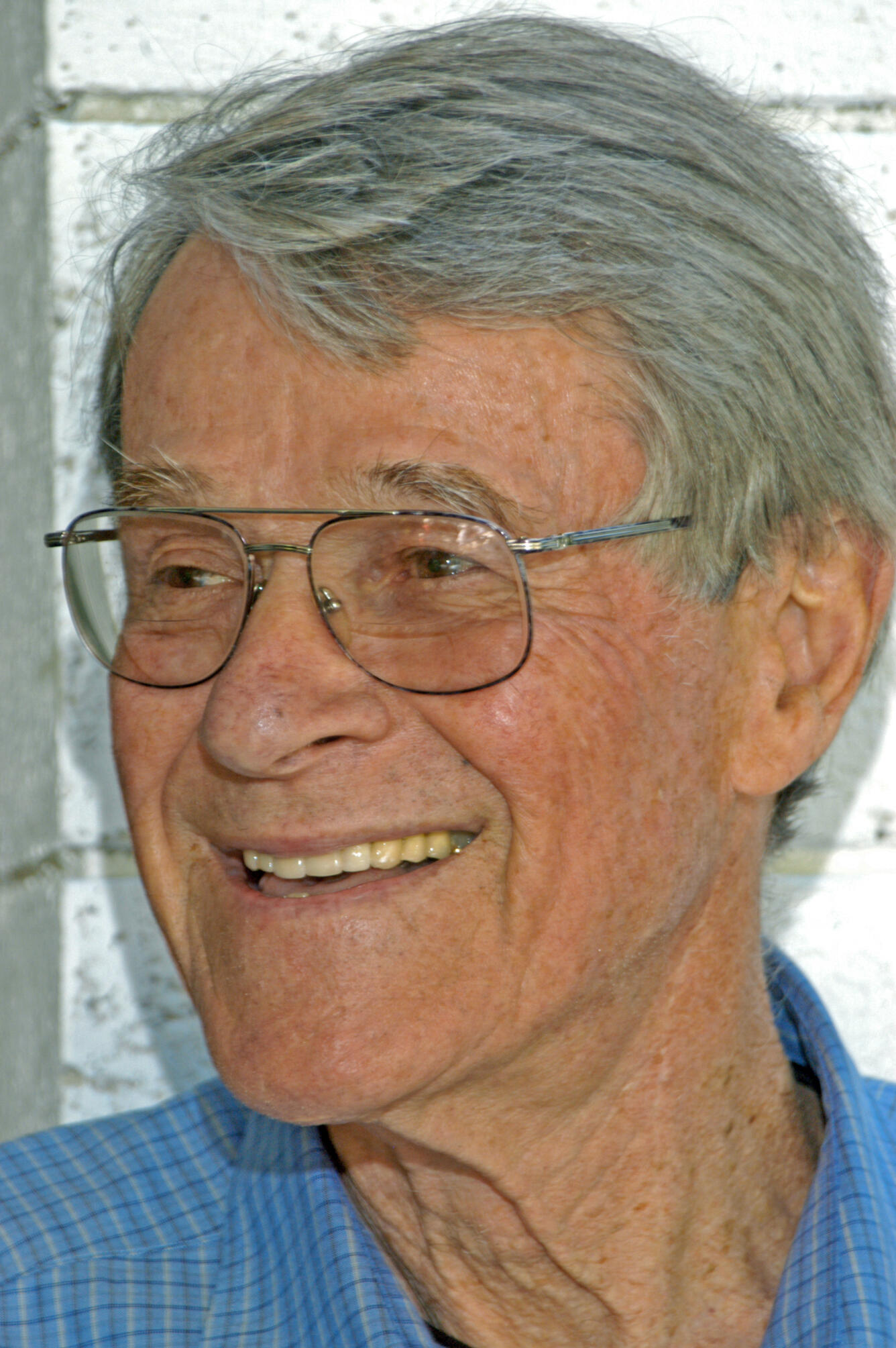 Headshot of a grey-haired main in glasses, laughing