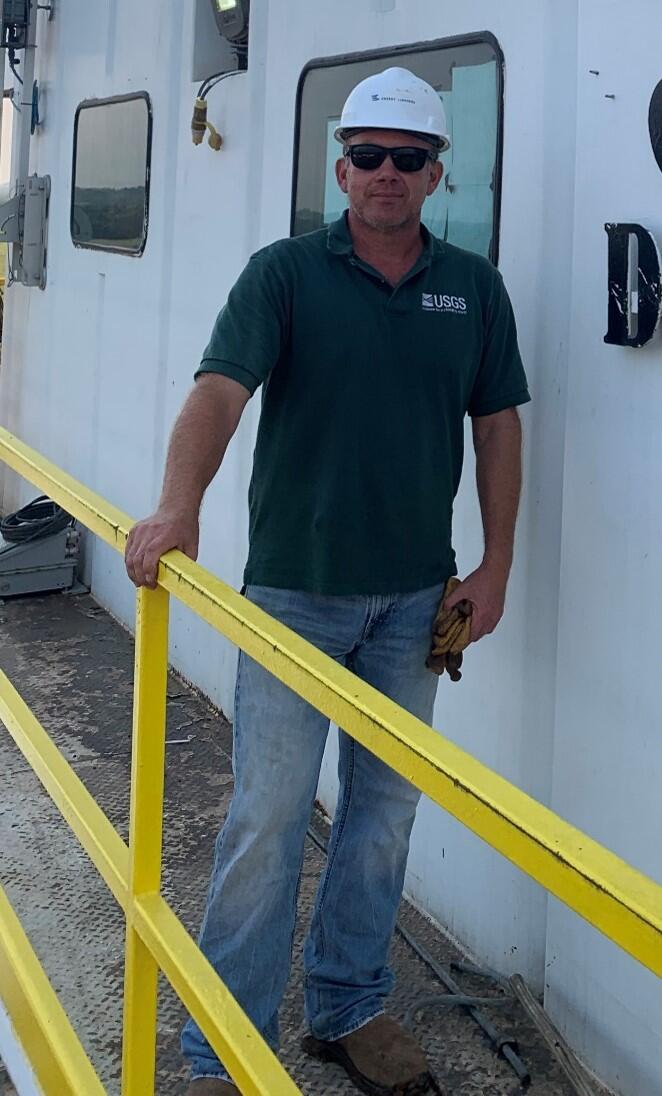 Jason Masoner wearing a hard hat and standing on a corrugated metal walkwal
