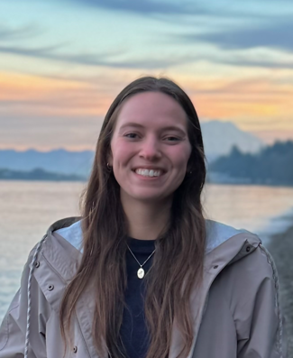 Smiling person with seashore, mountains, and sunset