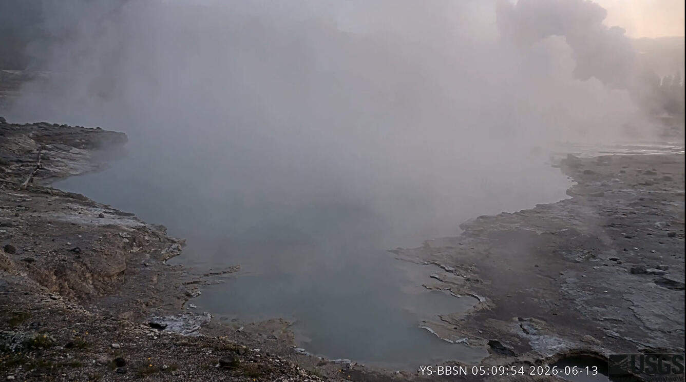 steaming blue pool in low-light dawn conditions with an explosive steam plume in the background