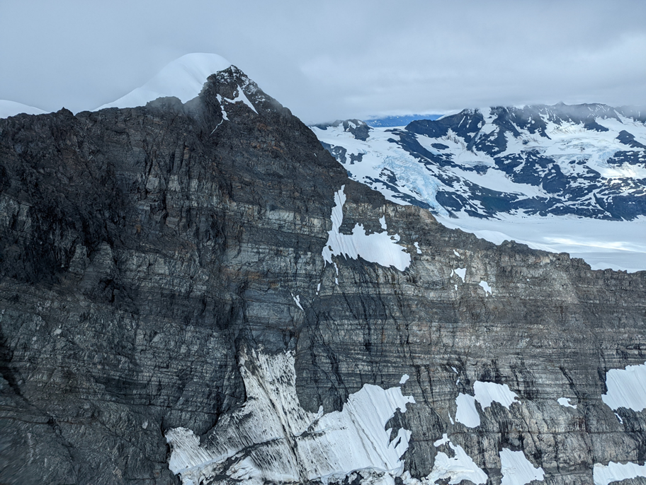 Side view of a rocky peak partially covered in snow