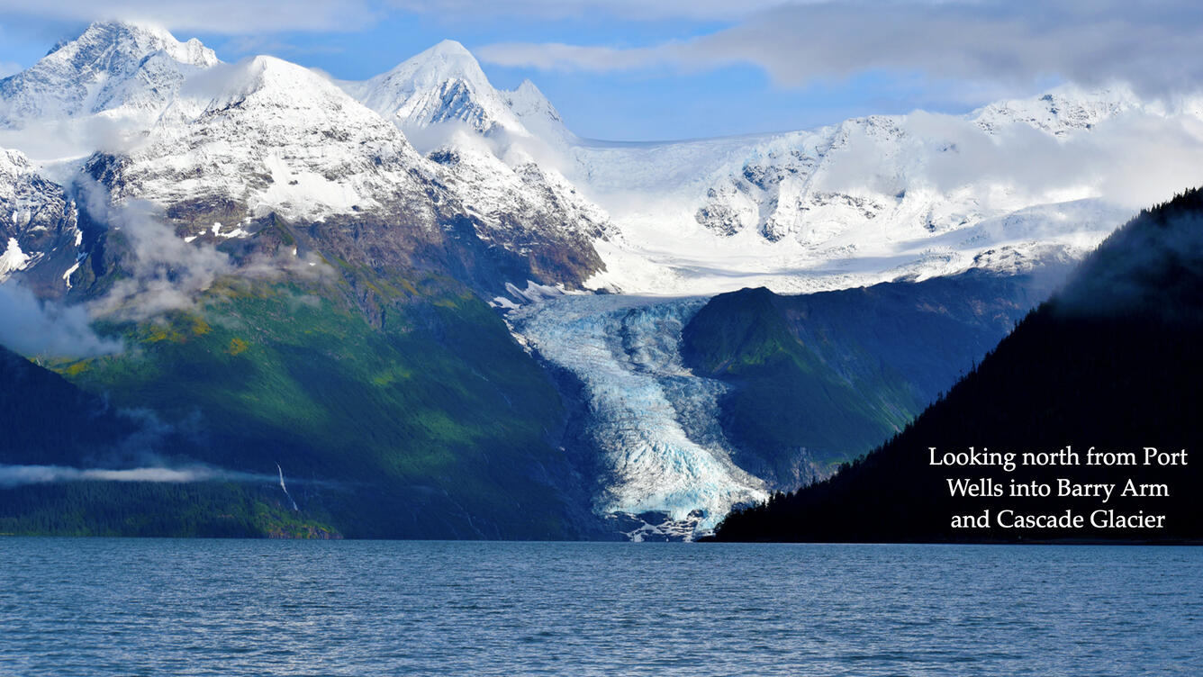 A glacier flowing between snow-capped mountains