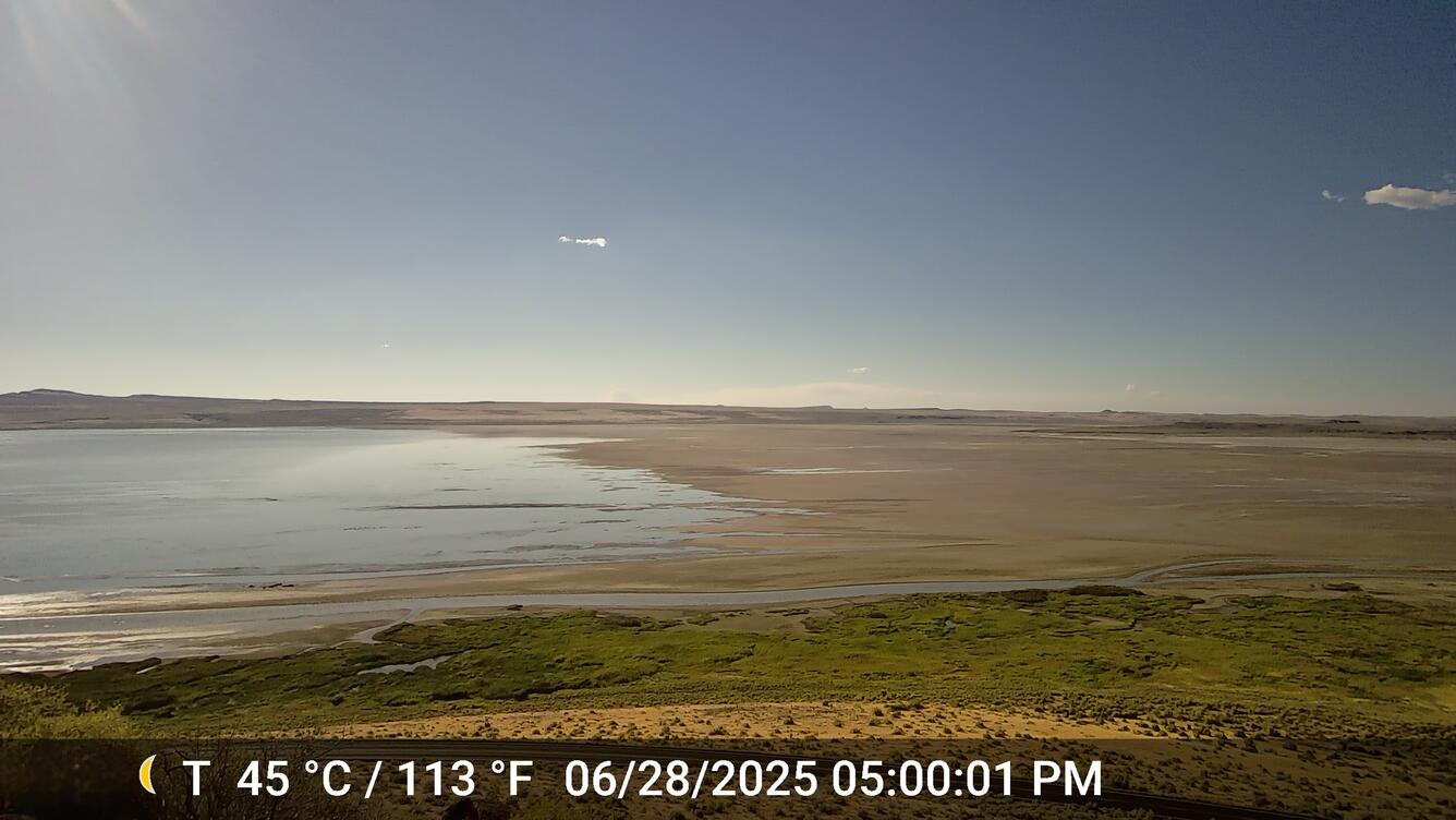 shallow lake water on the left and exposed lakebed on the right. Clear, sunny day.