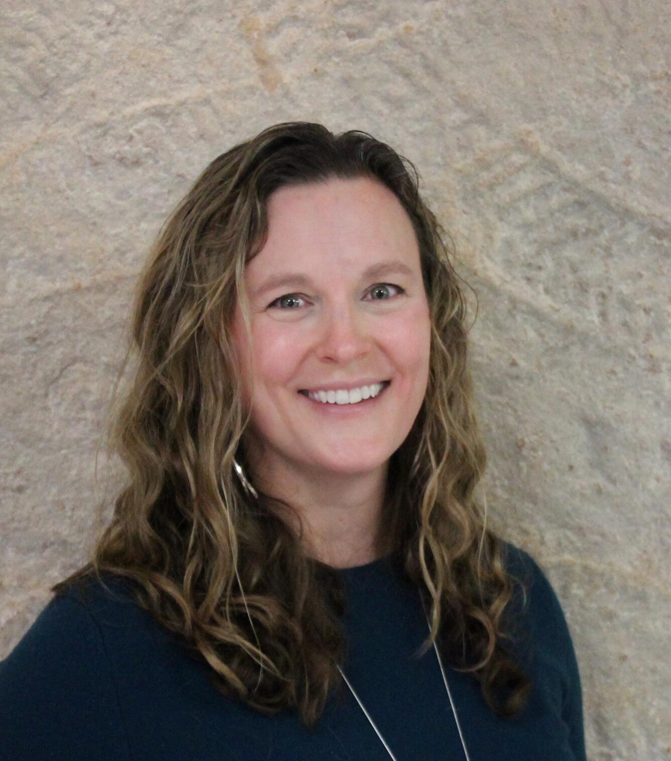 Smiling woman pictured against large fossil imprinted wall