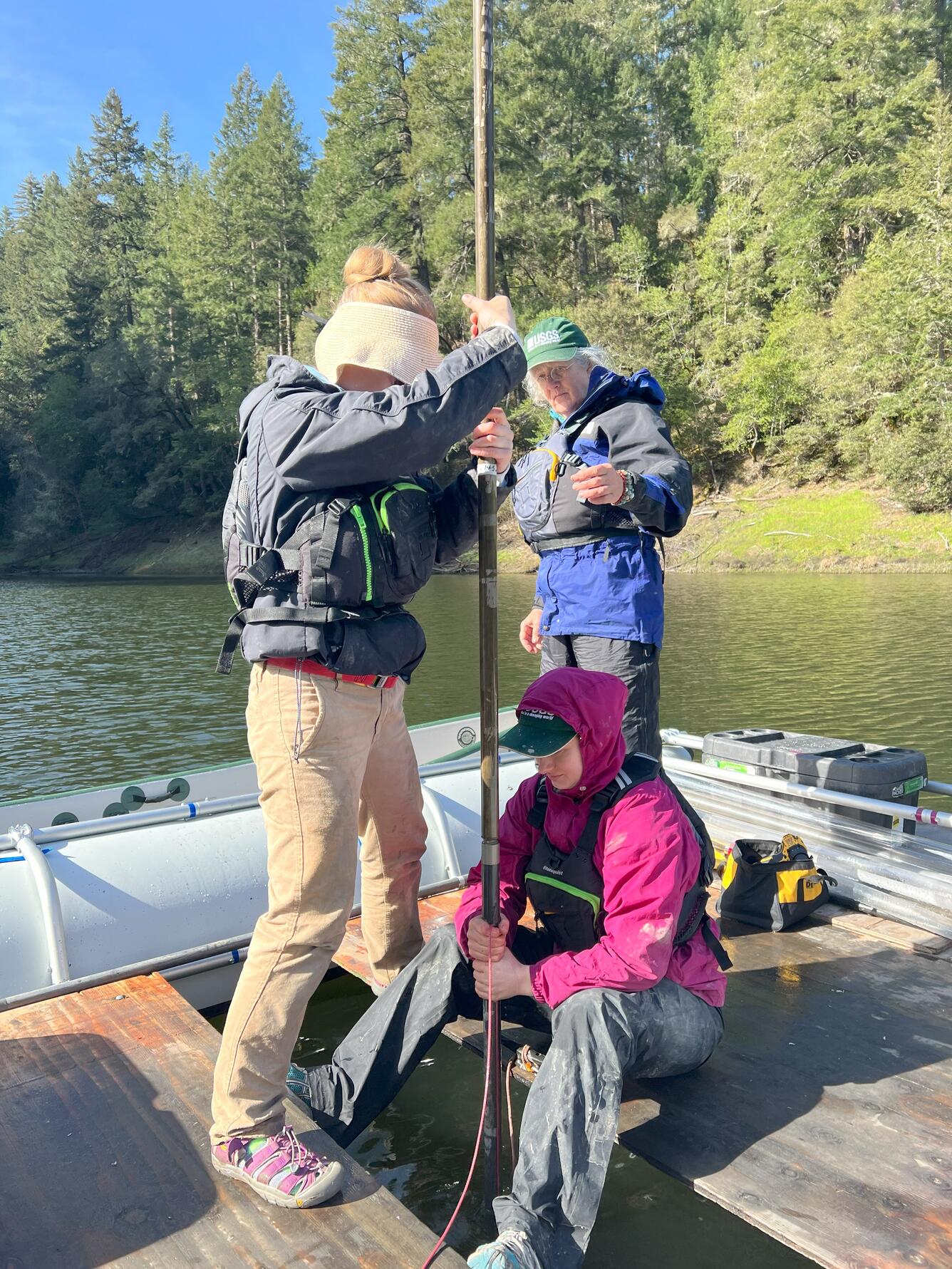 three scientists on a raft preparing to extract a sediment core