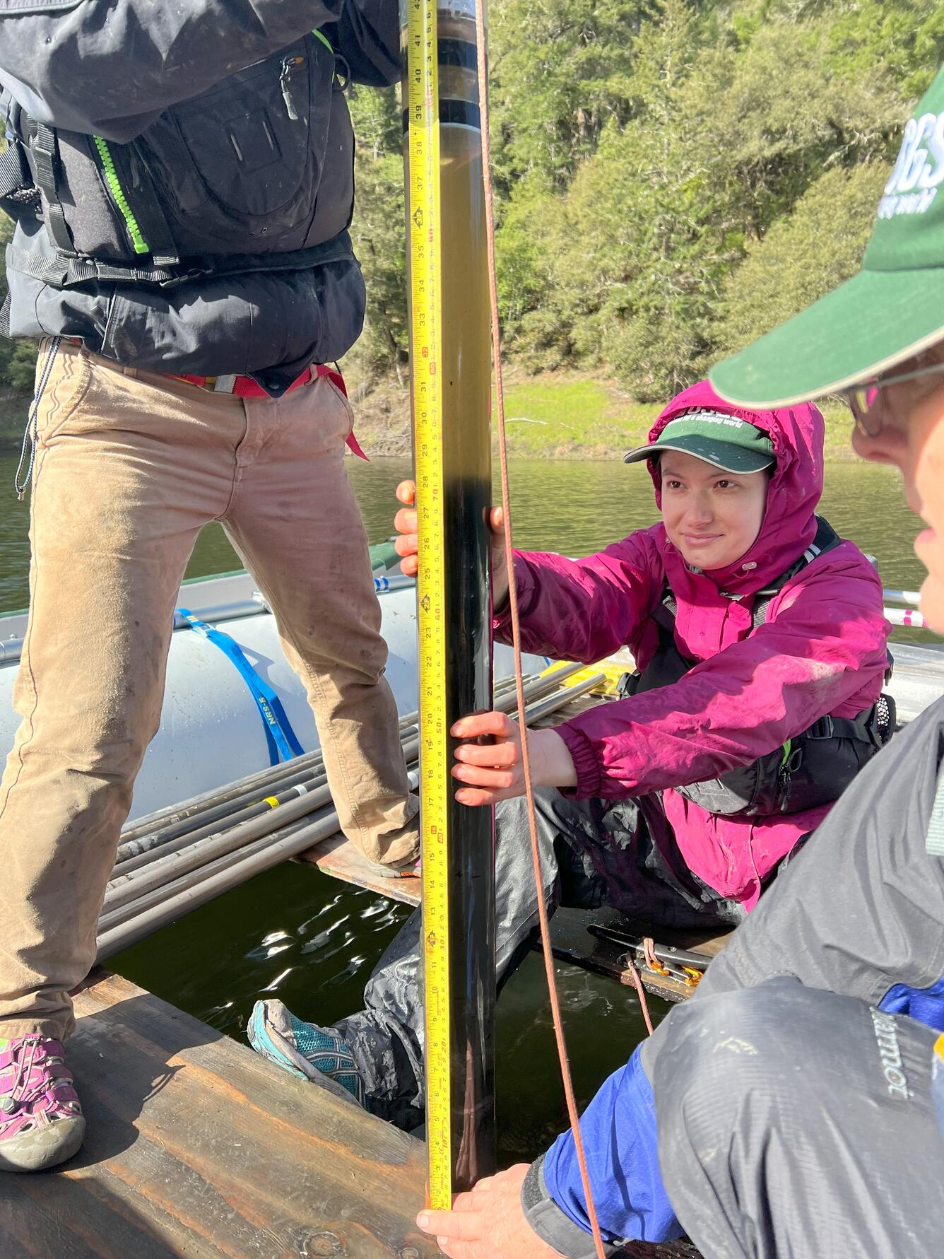 three scientists measure a freshly extracted lake sediment core