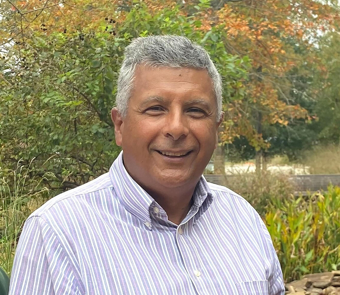man wearing a striped shirt standing near trees