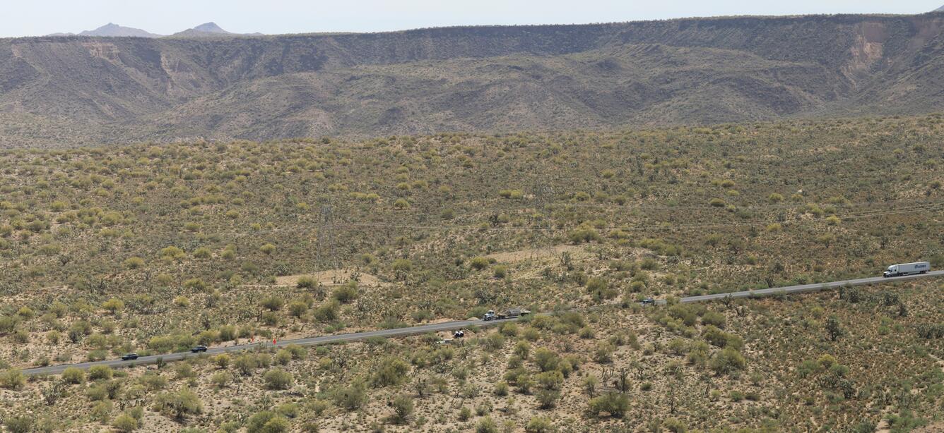 road in front of a hillslopes that are covered with shrubs and other vegetation