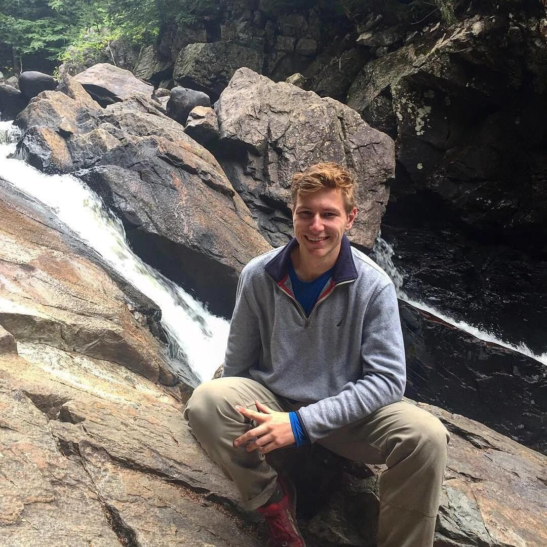 Image of USGS employee Mike Mahoney squatting near a rock water feature
