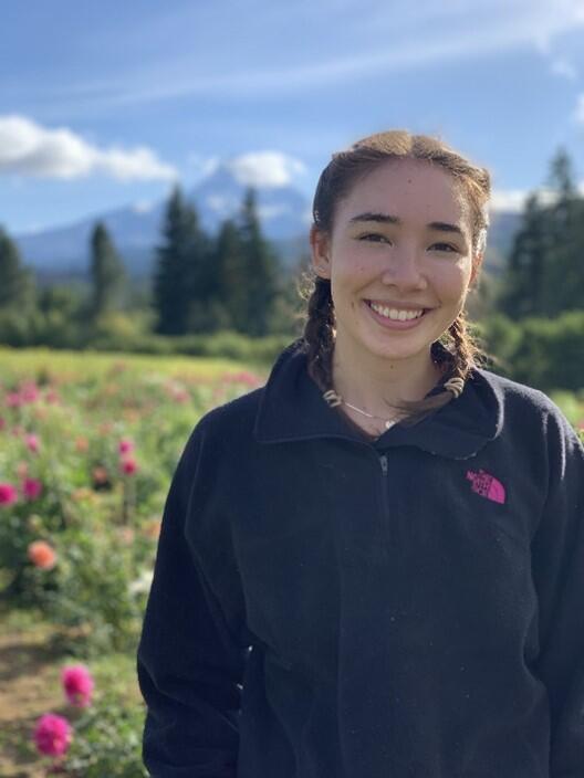 Headshot of a woman smiling in front of a field of flowers and a mountain