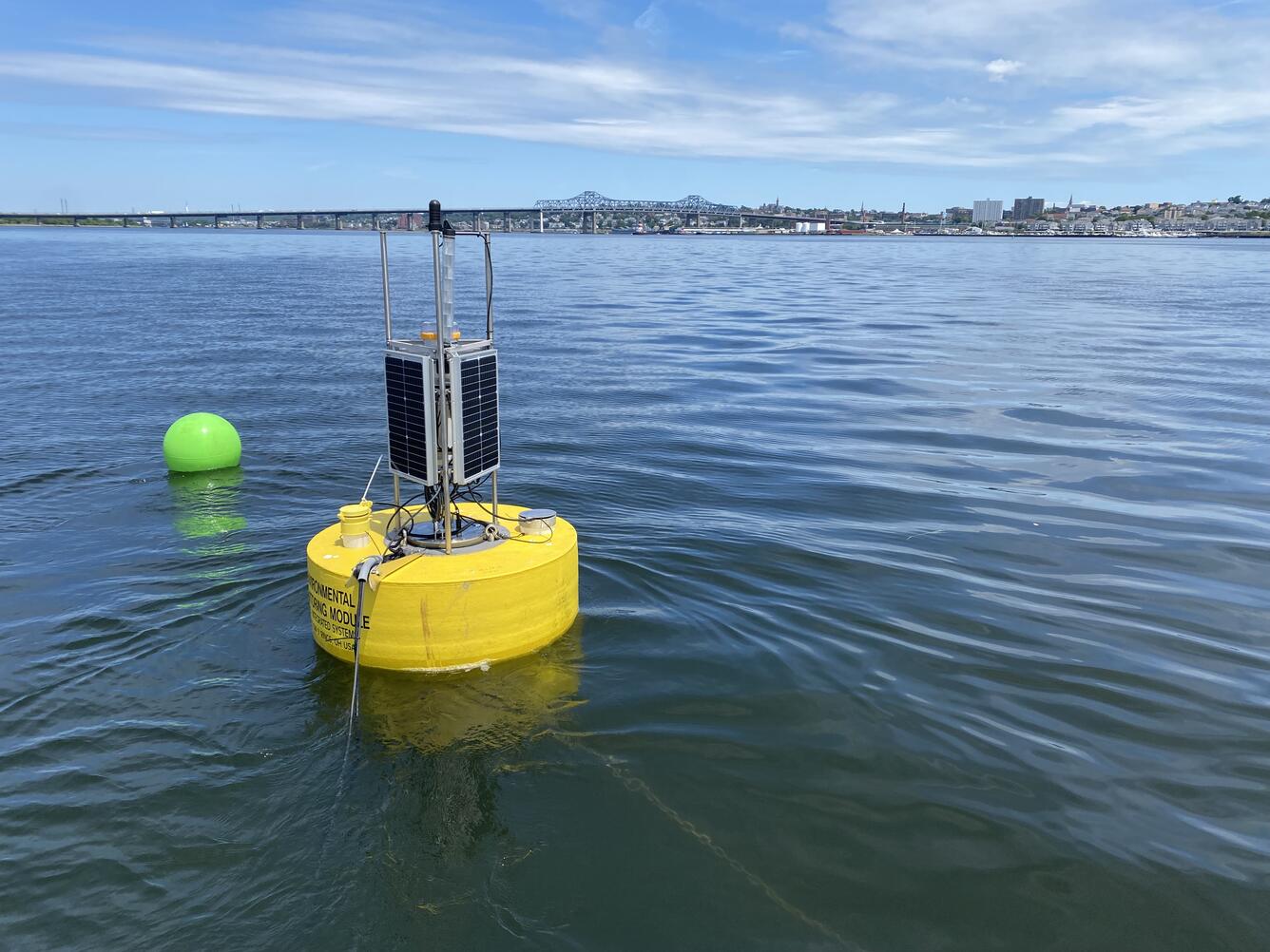 A yellow buoy holding water quality equipment floating in a bay.
