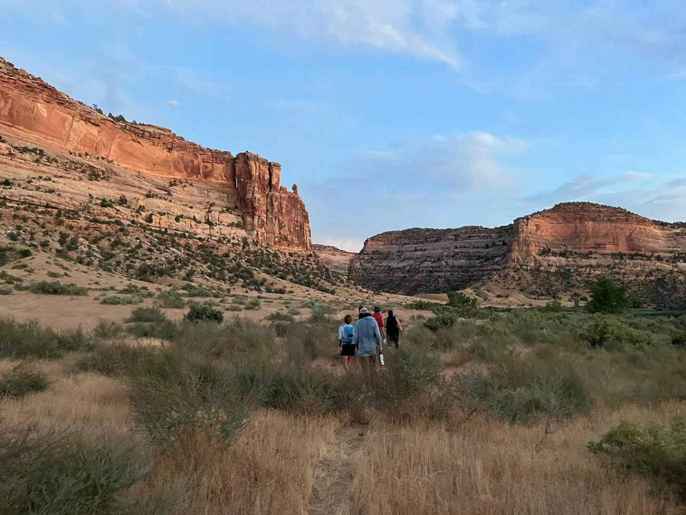 People walk in grassland towards canyons