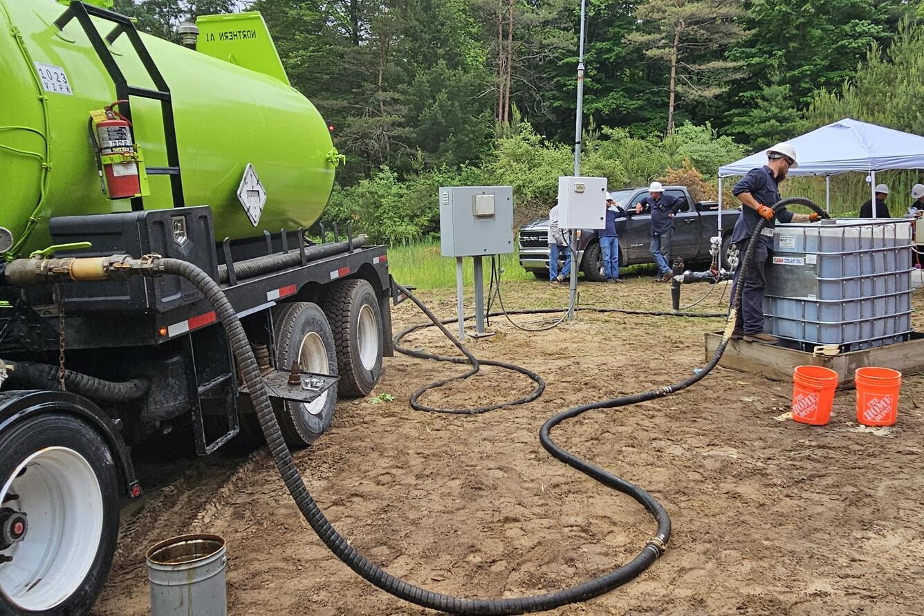 A man uses a tube to inject yeast extract into a pipe that will carry it to an underground coalbed. 
