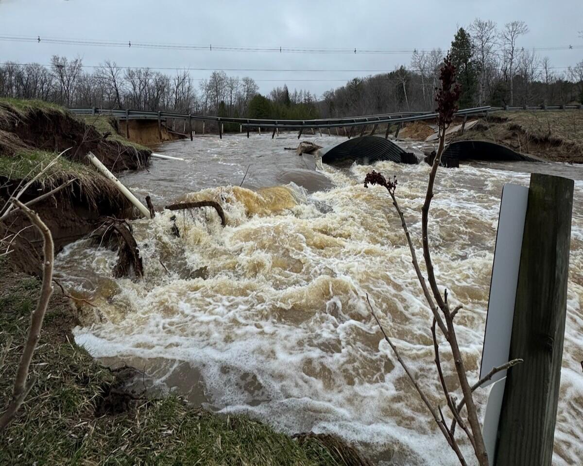 Washed out bridge over raging flood waters on a gray day