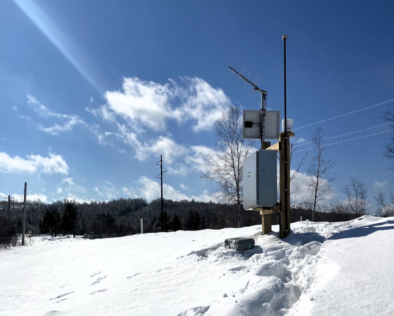 Streamgage surrounded by snow on a sunny winter day