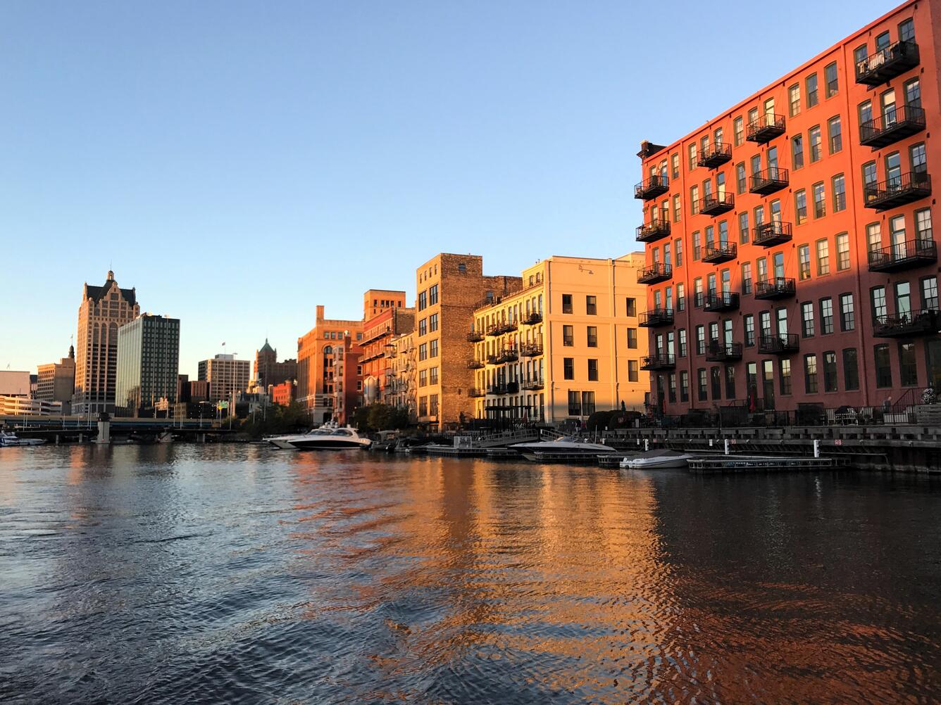 Sunset illuminating buildings in a city with a river in foreground