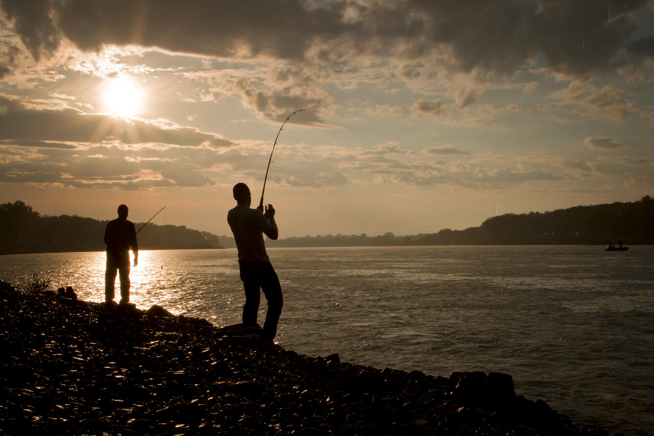 Two people fishing at sunset.