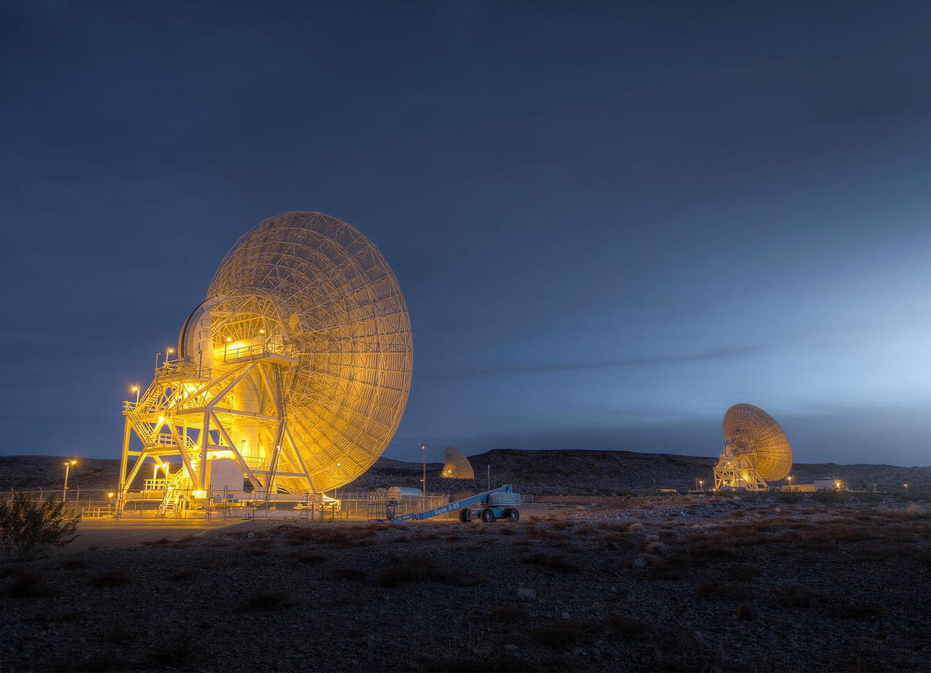 A beautiful photo of the Deep Space Network satellite dish at Goldstone, California taken at night time. Dish is lit up wonderfully and glows brightly.