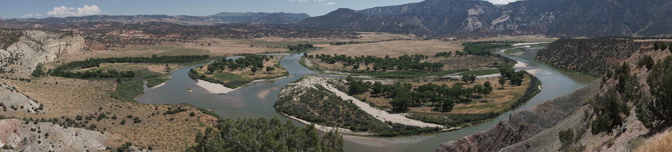 panoramic, aerial shot of a river bending through shrublands and mountains