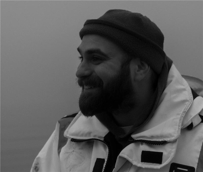 Black and white image of Neel Hodgkinson in a float coat.