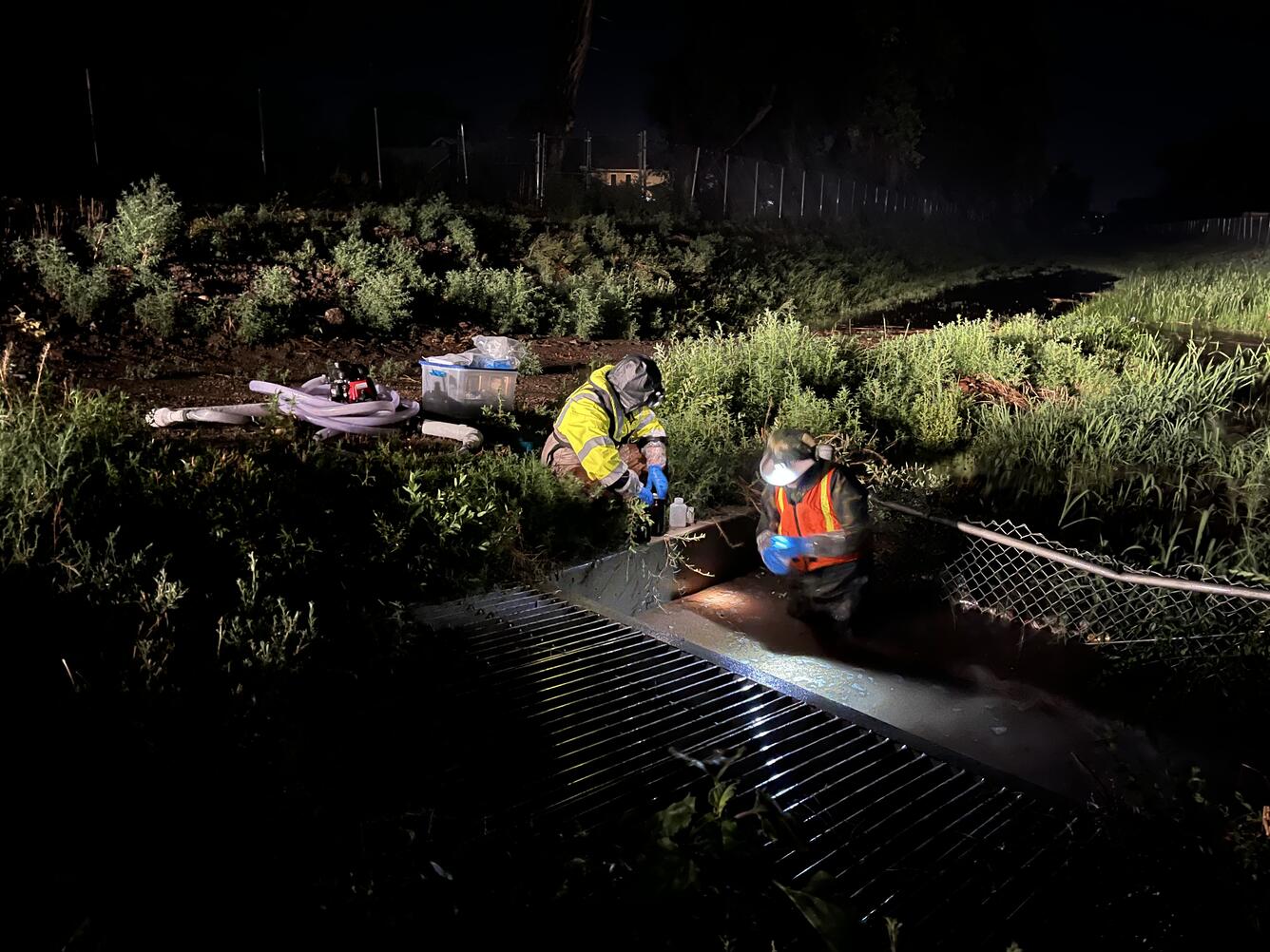 Two USGS employees sampling surface water in the dark during a rainstorm. 